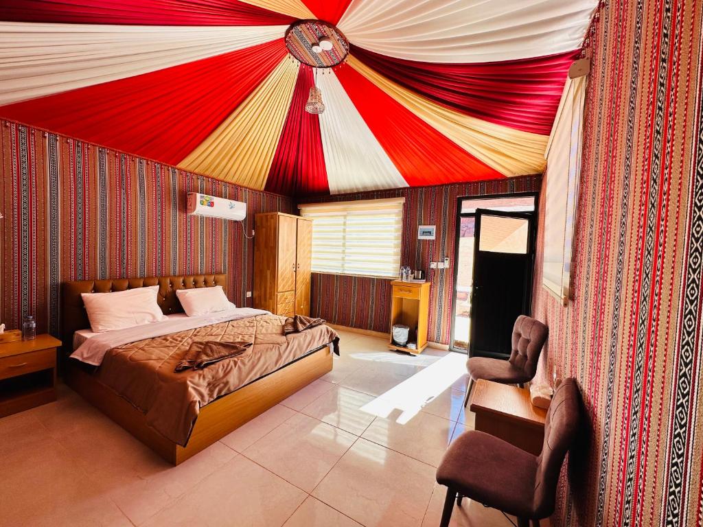 Un dormitorio con una cama con un techo rojo y amarillo. en Wadi Rum - Deluxe Tent, en Wadi Rum