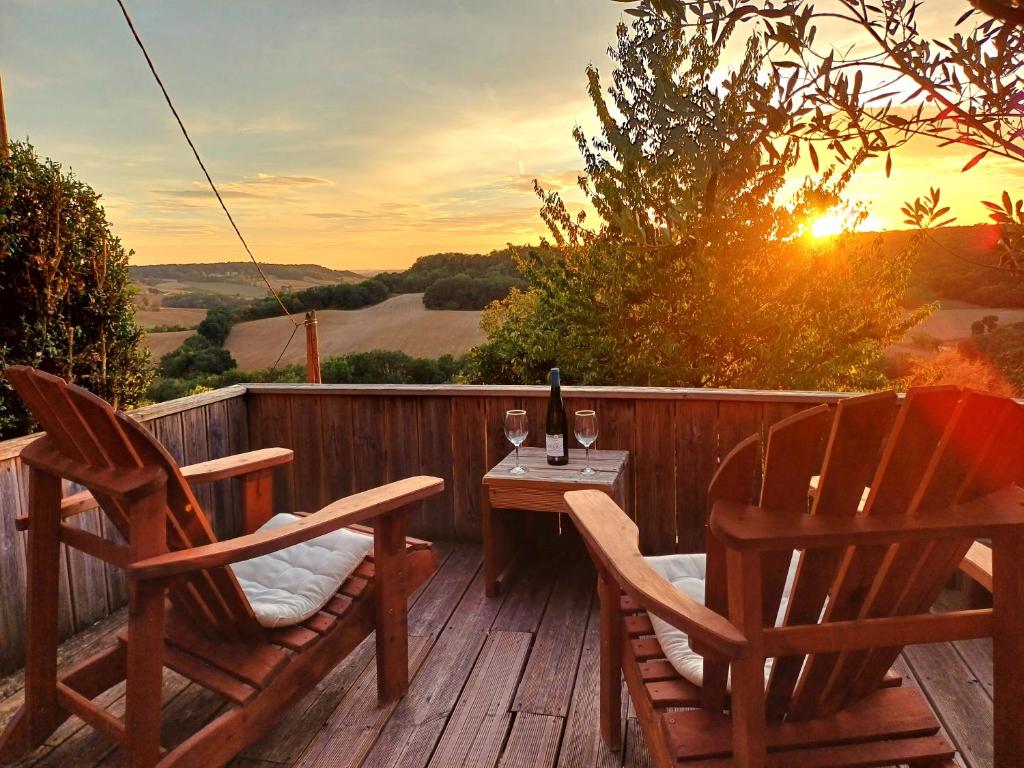 una terrazza con due sedie e un tavolo con una bottiglia di vino di Les Terrasses de Flaugnac a Flaugnac