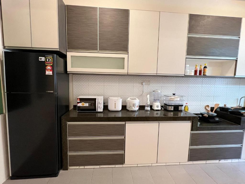 a kitchen with a black refrigerator and white cabinets at myROOM @ Mandalay Georgetown, Off Jln Burma, Gurney Drive in George Town