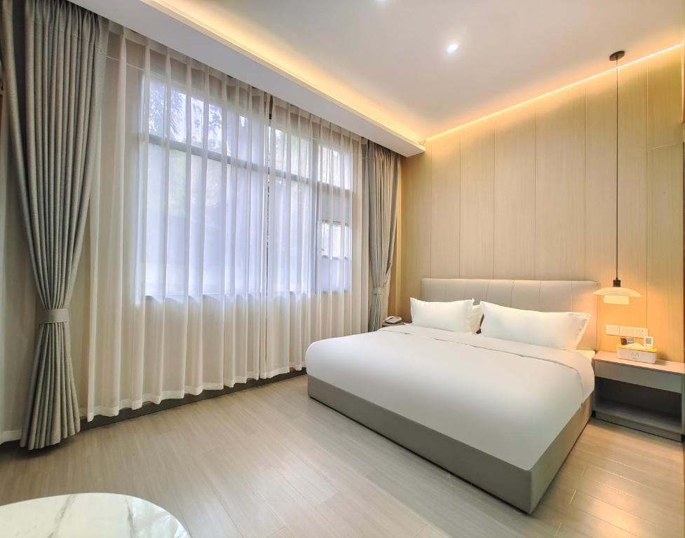 1 dormitorio con 1 cama blanca grande y ventana grande en Airport Dream B&B - Tianfu International Airport Branch, en Jianyang