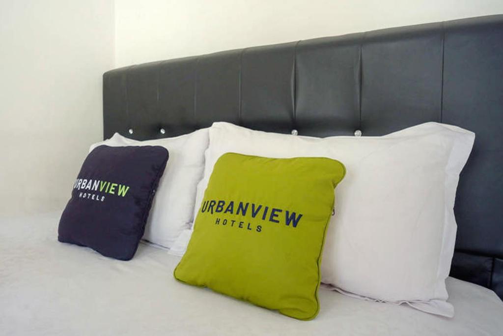 a group of pillows sitting on top of a bed at Urbanview Grand Lotus Hotel by RedDoorz in Purwokerto