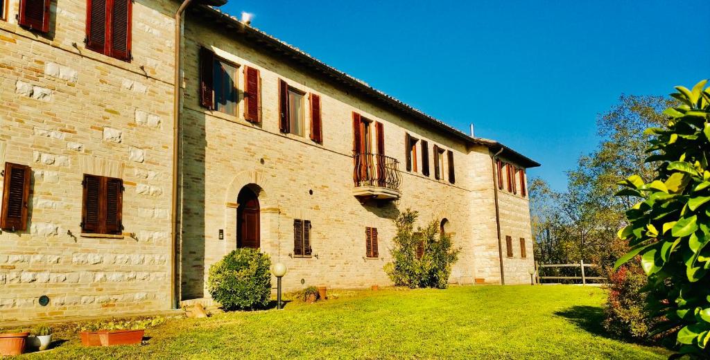 um grande edifício de tijolos com um quintal em frente em Ca' Tomassino Holiday Apartments em Urbino