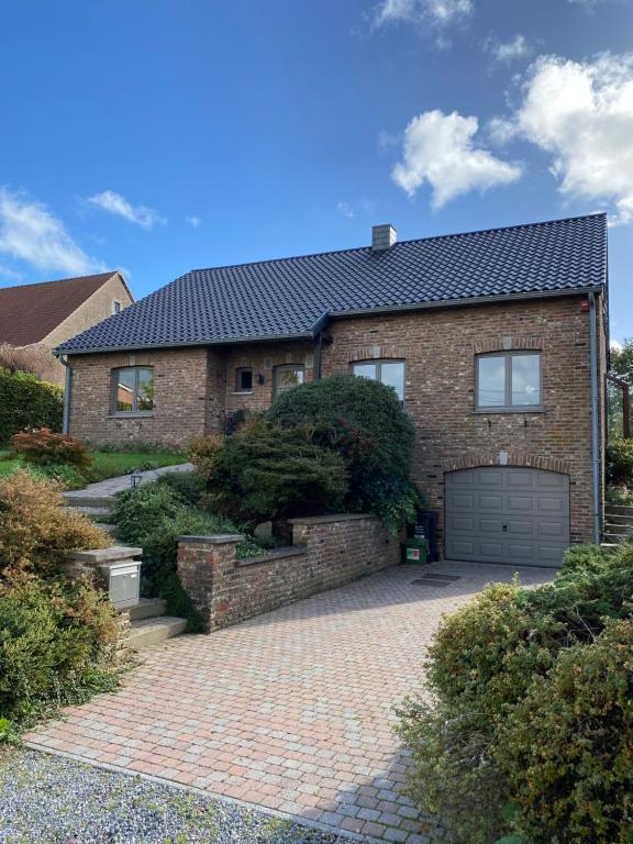 a brick house with a garage on a brick driveway at Le Logis du Plateau in Herve