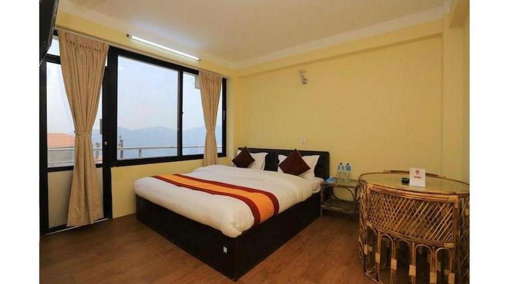 een slaapkamer met een bed en een groot raam bij Hotel Bihani in Dhulikhel