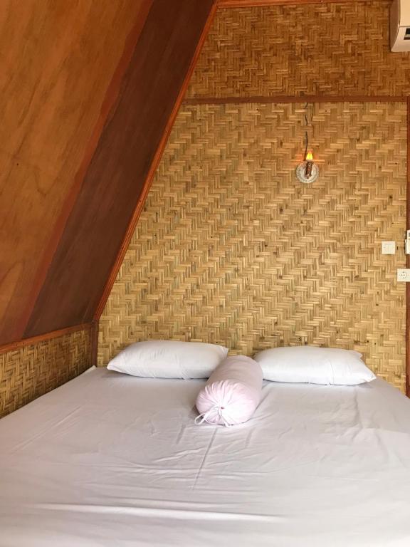 ein Bett mit zwei weißen Kissen und einer Ziegelwand in der Unterkunft Muni's Terrace Bungalow in Kotaraja