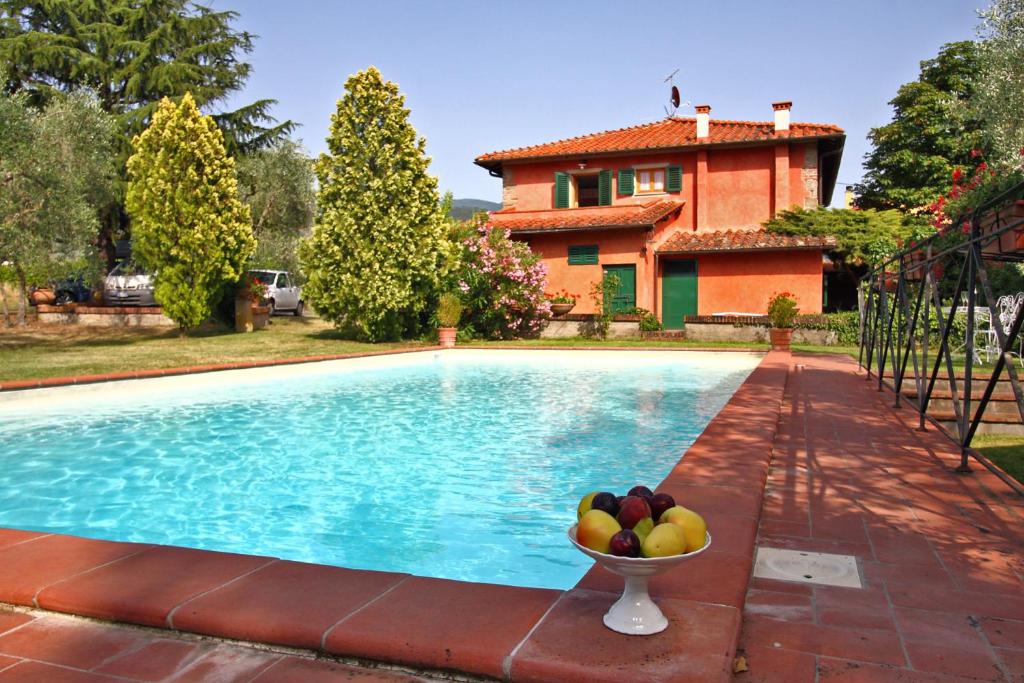 a bowl of fruit sitting next to a swimming pool at Villa Perla - Homelike Villas in Reggello