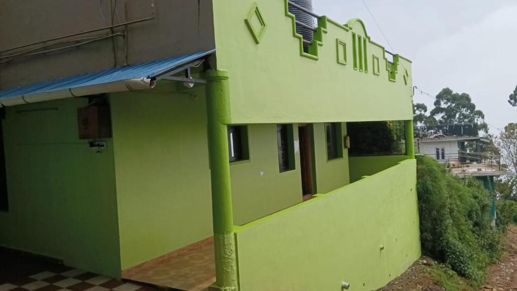 un bâtiment vert avec un panneau sur son côté dans l'établissement Green Star Bungalow, à Kodaikānāl