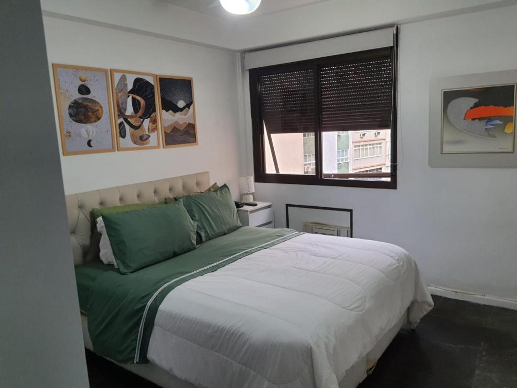 sypialnia z łóżkiem z zieloną pościelą i oknem w obiekcie Plaza Elysees 202 w mieście Rio de Janeiro