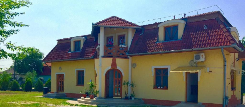 uma casa amarela com um telhado vermelho em Akácliget Gyógy-és Strandfürdő em Karcag