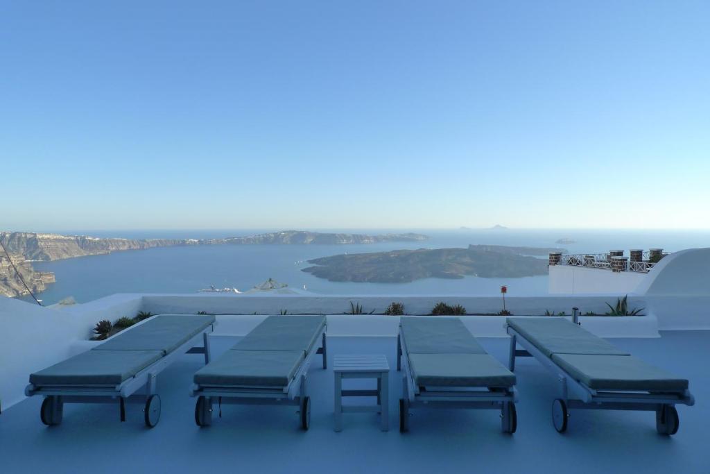 a group of tables and benches on a roof at Altana Cliffside Villas in Imerovigli