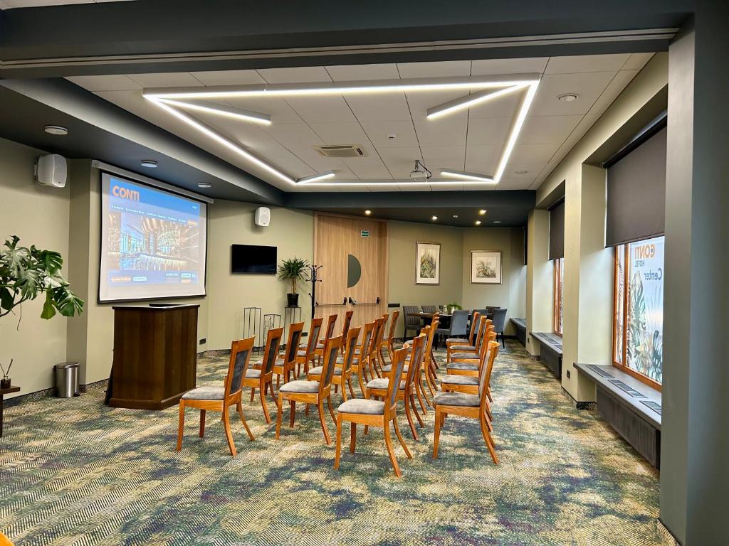 a conference room with chairs and a podium and a screen at CONTI HOTEL VILNIUS, Conference Centre, Restaurant & Bar in Vilnius