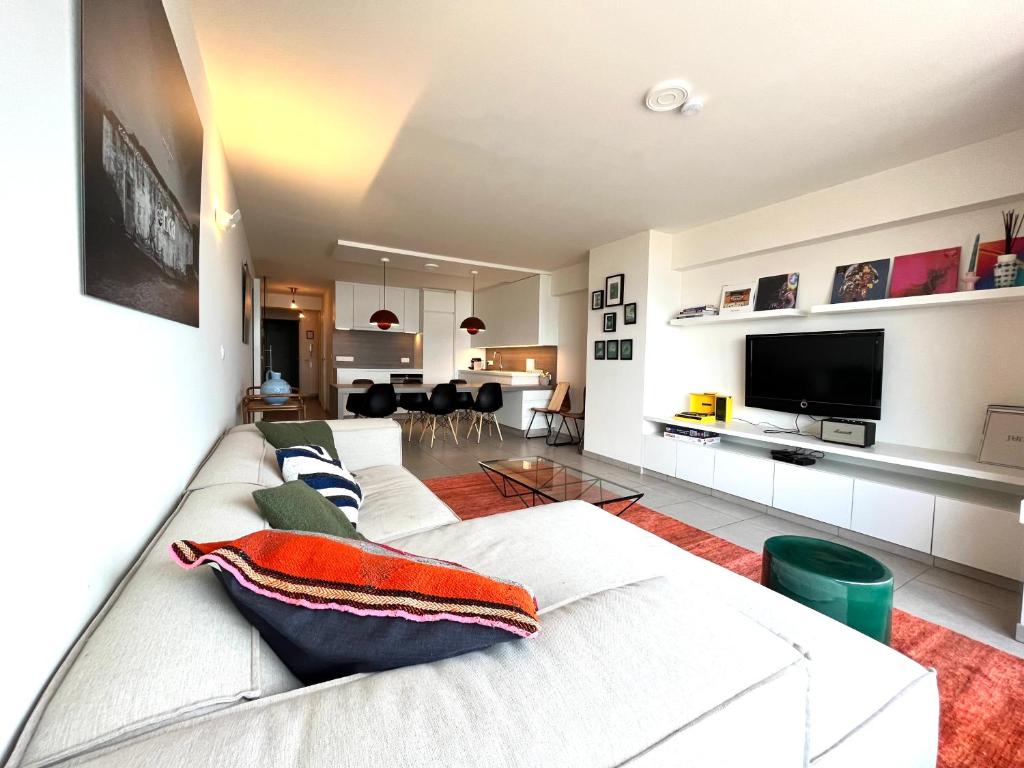 a living room with a white couch and a tv at AMAZING Beach View Apartment type 28 in Ostend