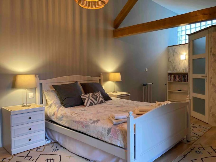 Un dormitorio con una gran cama blanca con dos lámparas. en Stunning rural gem with pool in southwest France, en Brie-sous-Barbezieux
