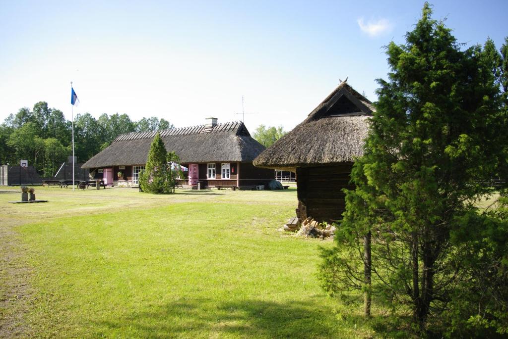 ein Haus mit einem Strohdach und einem Grasfeld in der Unterkunft Kase Holiday Center in Paiküla