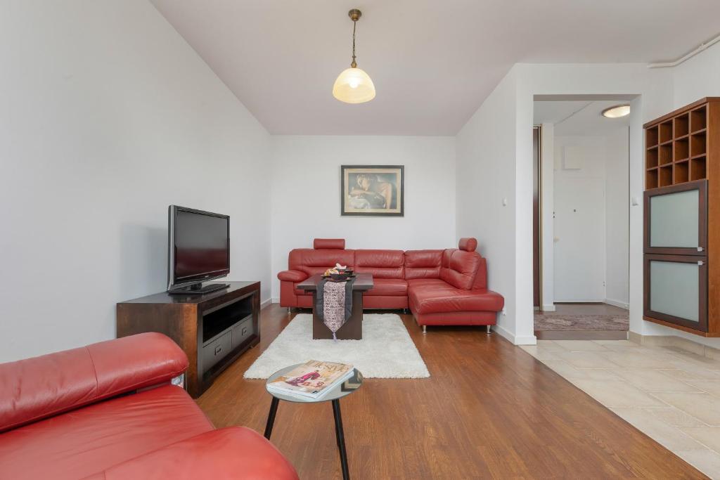 a living room with red couches and a tv at Cozy Apartment near Airport by Renters in Warsaw