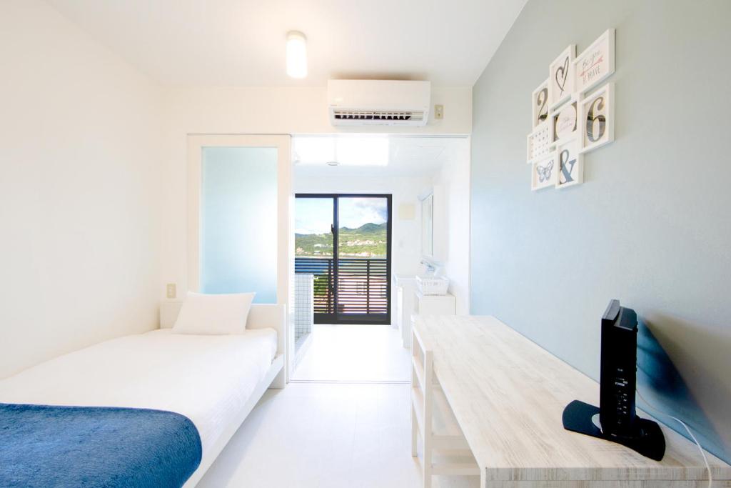 a white bedroom with a bed and a desk at E-horizon Resort Condominium Sesoko in Motobu