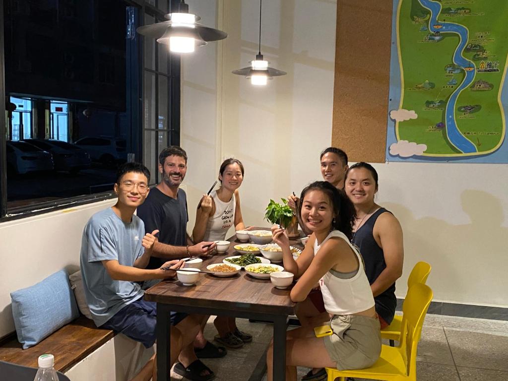 un grupo de personas sentadas alrededor de una mesa comiendo comida en Pomelo Hostel, en Yangshuo