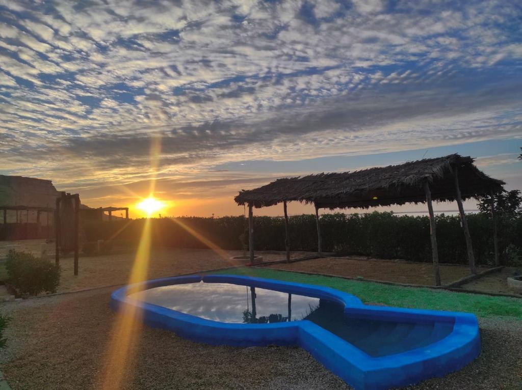 a sunset with a pool in the middle of a yard at Eswan Hotel in Siwa