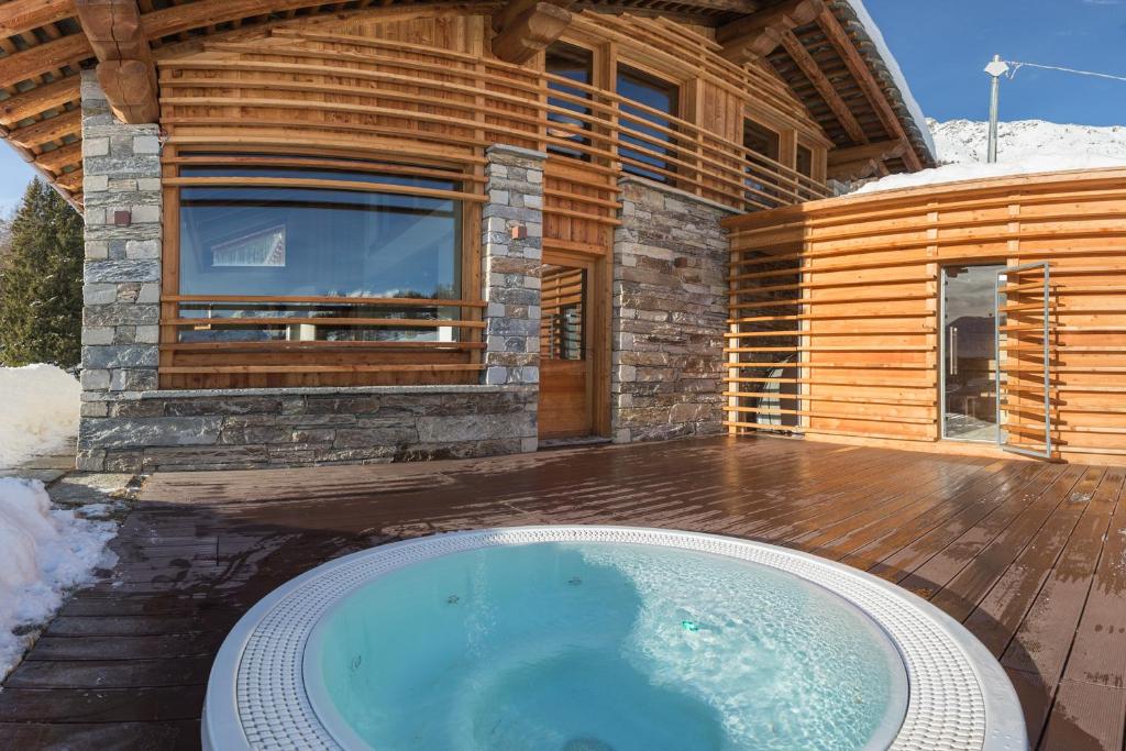 a large hot tub in front of a log house at Lavarets Chambres d’Hôtes in Ayas