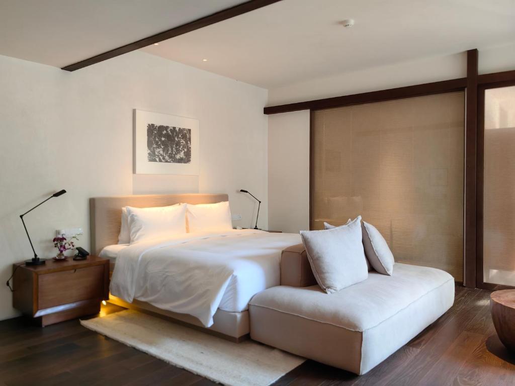 una camera con un letto bianco e un divano di Jiangnan House Changyuan a Suzhou