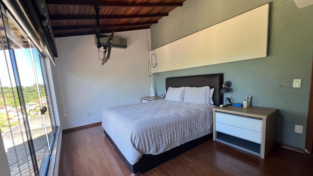 1 dormitorio con cama y ventana grande en Tartaruga 2A, Suite privada e moderna., en Búzios