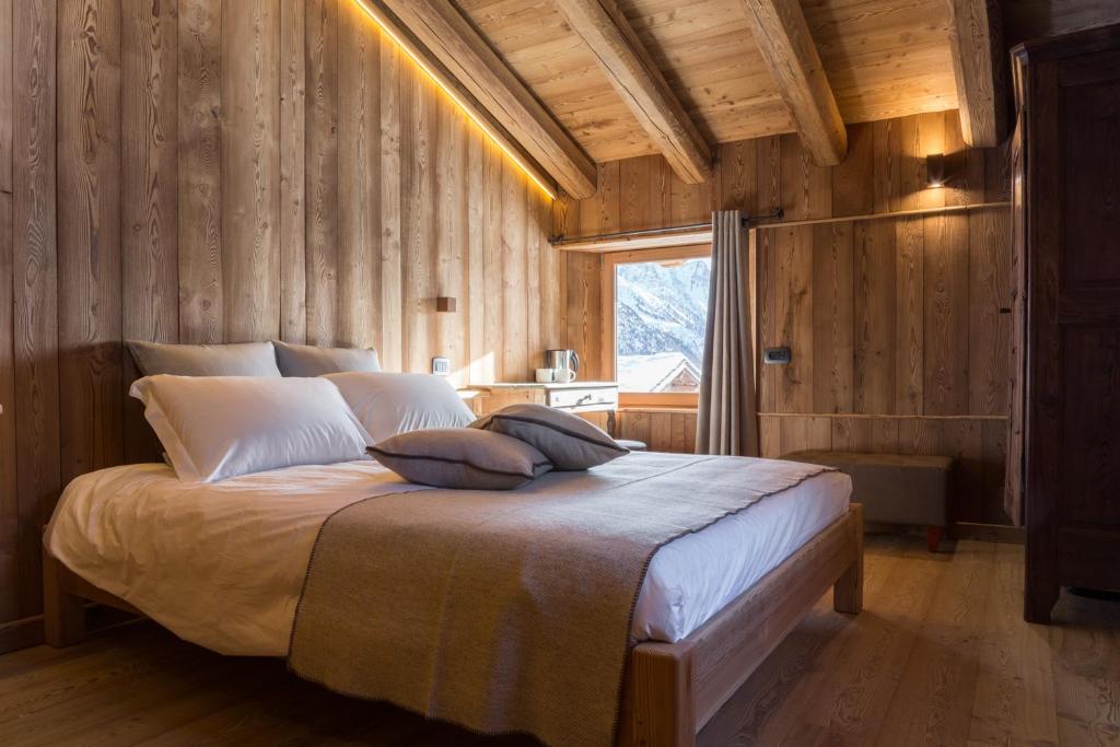 sypialnia z dużym łóżkiem w drewnianej ścianie w obiekcie Lavarets Chambres d’Hôtes w mieście Ayas