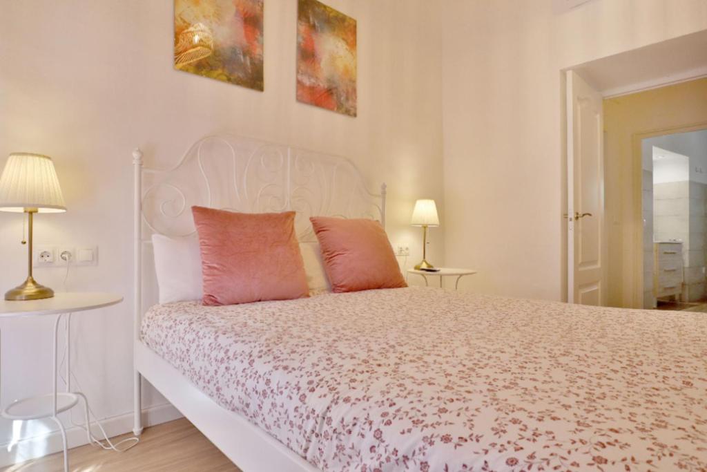 ein Schlafzimmer mit einem weißen Bett mit rosa Kissen in der Unterkunft Posada de la Judería II in Córdoba