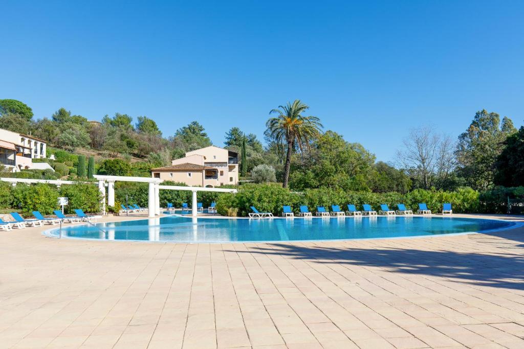 une grande piscine avec des chaises et un complexe dans l'établissement Les Parcs De Grimaud YourHostHelper, à Grimaud