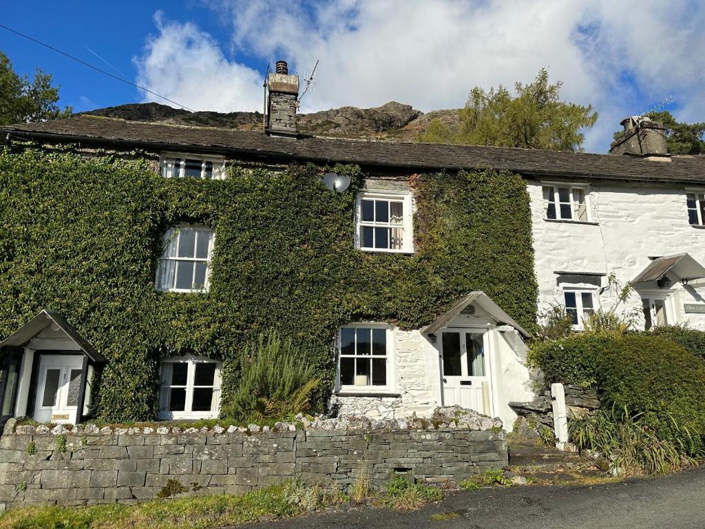 an ivy covered house with a brick wall at The Sheiling, Traditional Lakeland Cottage, Coniston in Coniston