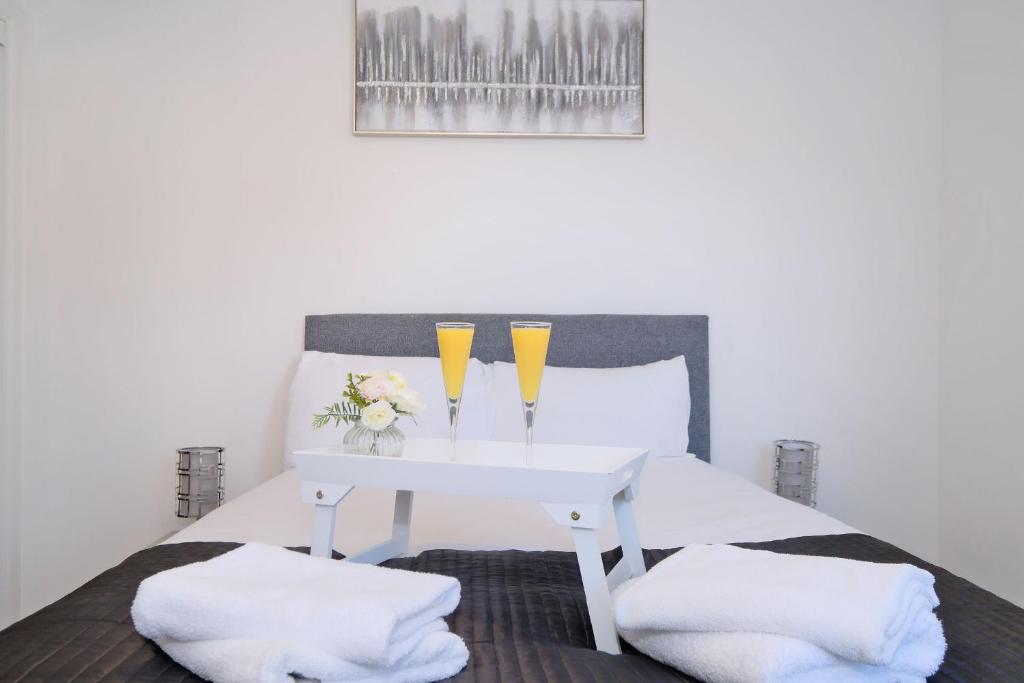 a bed with a white table with two glasses on it at Orange Apartments Belgrave Mansions in Aberdeen