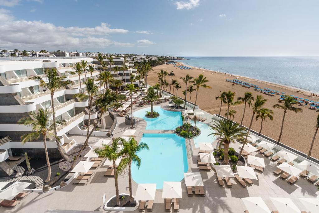 プエルト・デル・カルメンにあるPlus Fariones Suite Hotelのスイミングプールとビーチのあるリゾートの空からの景色を望めます。