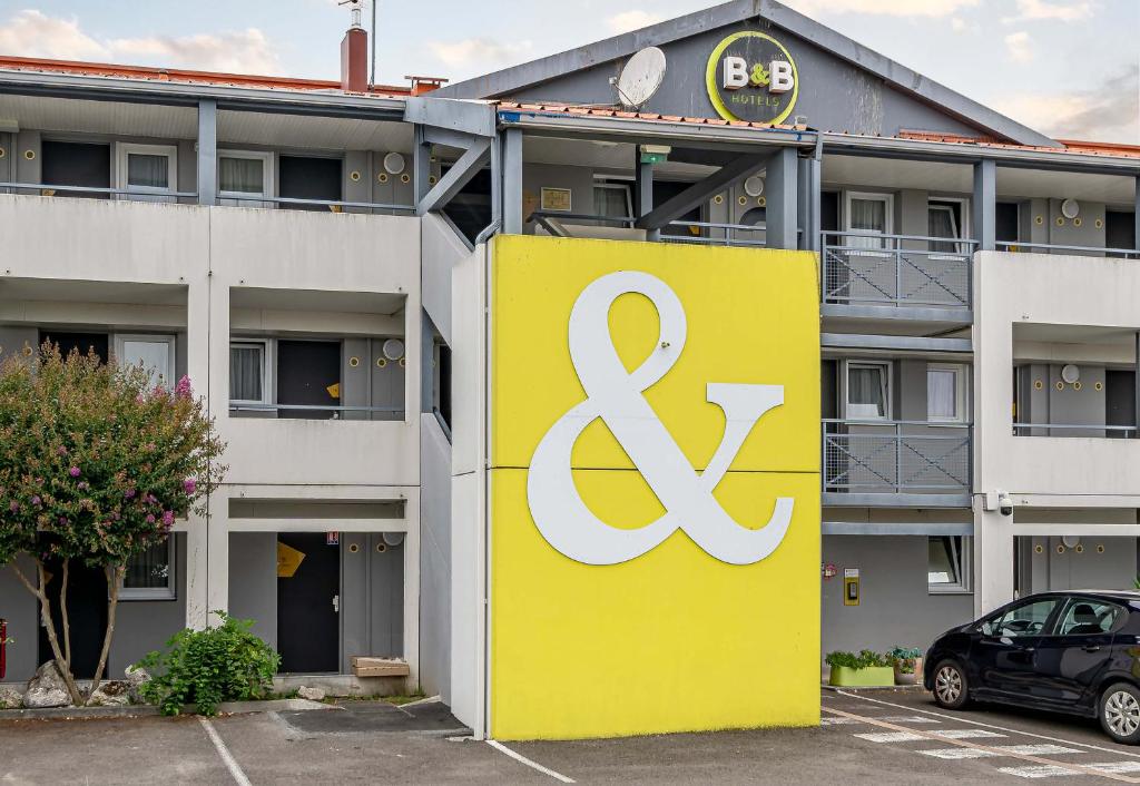 a yellow and white sign in front of a building at B&B HOTEL Bordeaux Sud in Villenave-dʼOrnon