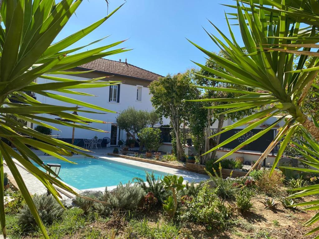 a villa with a swimming pool and palm trees at LE FIGUIER in Cabestany