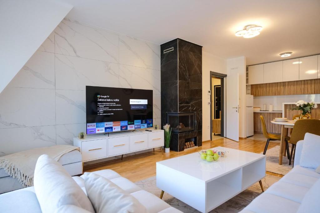 a living room with a white couch and a tv at Lux Sara Apartments in Visoko