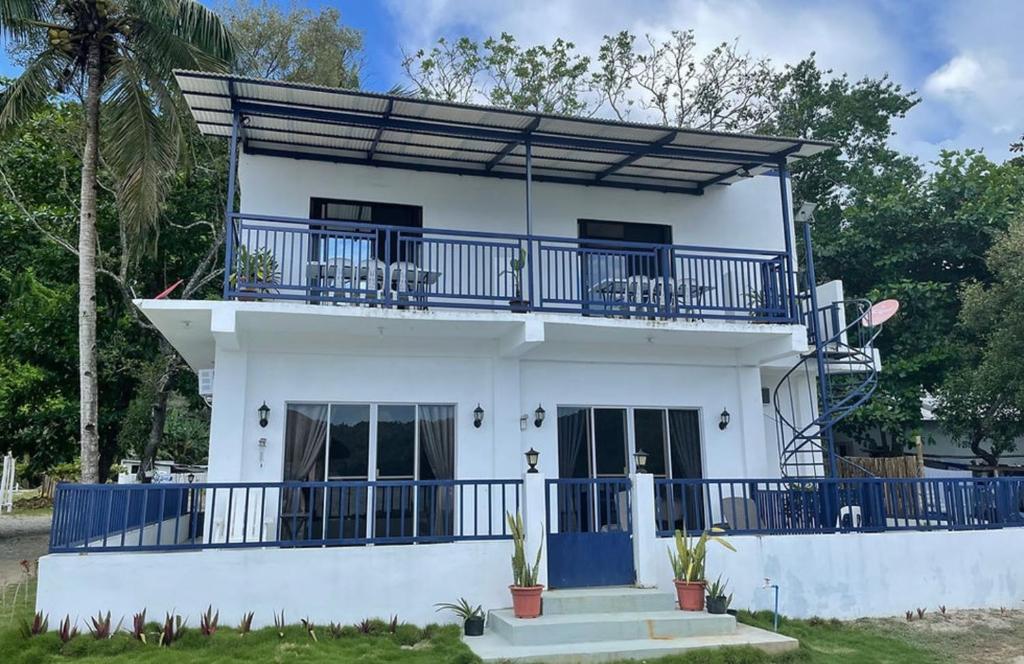 a white house with a blue balcony at Lopez Beach Resort in Sipalay