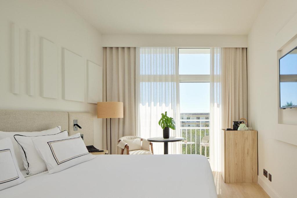 a bedroom with a white bed and a large window at Meliá Lloret de Mar in Lloret de Mar