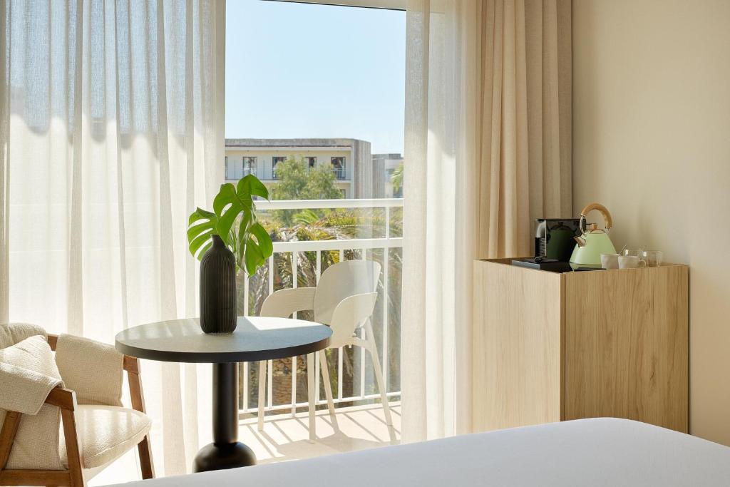 a room with a bed and a window with a table at Meliá Lloret de Mar in Lloret de Mar