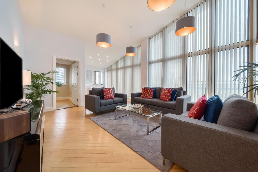 una gran sala de estar con sofás y TV. en Roomspace Serviced Apartments - The Courtyard Penthouse, en Londres