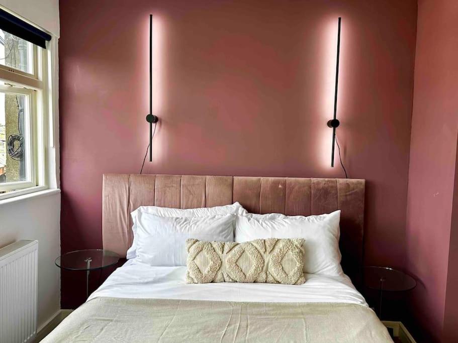 - une chambre avec un lit et deux lampes murales dans l'établissement Cozy Studio near Regent’s Park N9, à Londres