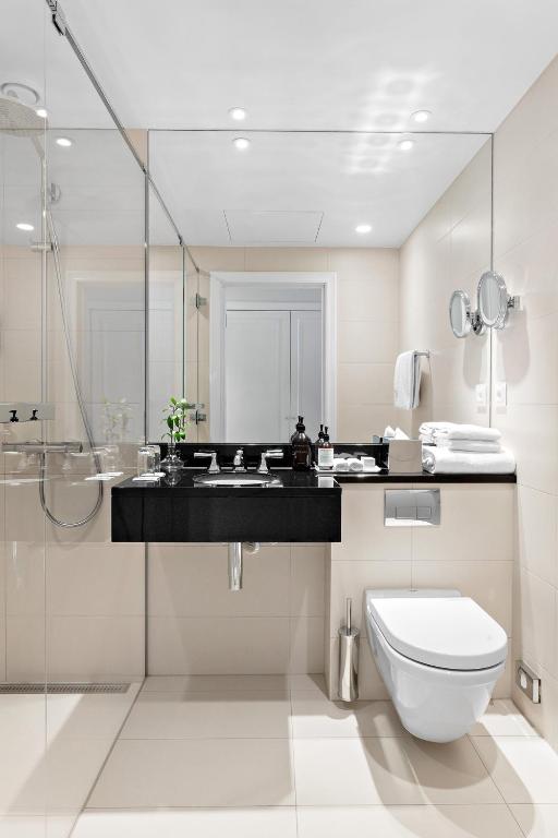 a white bathroom with a toilet and a sink at Hotel Continental in Oslo