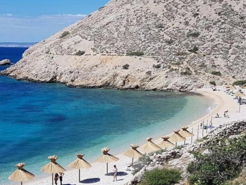 a beach with a bunch of umbrellas and the ocean at Apartman"Petra" in Krk