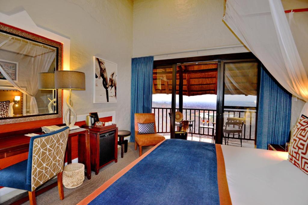 維多利亞瀑布的住宿－維多利亞瀑布野生酒店，配有一张床、一张书桌和一扇窗户的酒店客房