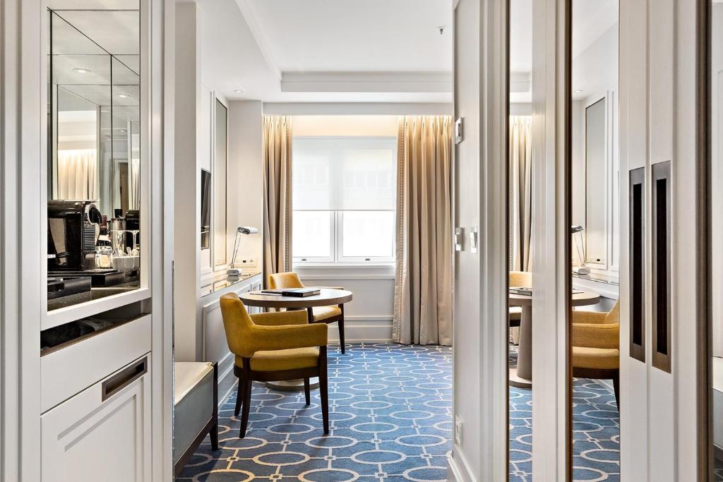 a living room with a table and a yellow chair at Hotel Continental in Oslo