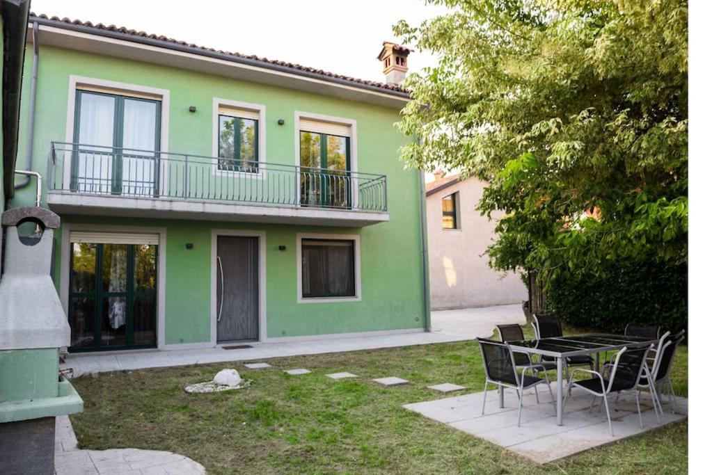 una casa verde con mesa y sillas en el patio en Luxury experience in Alba: Unesco hills' hearth, en Guarene