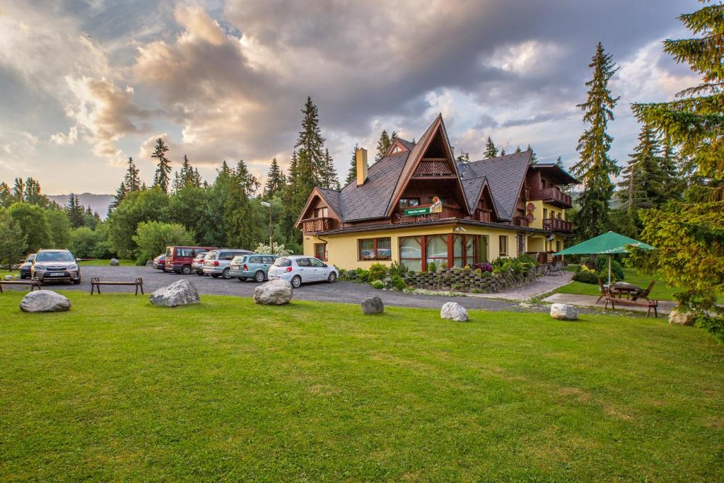 ein großes Haus mit Autos auf einem Parkplatz in der Unterkunft Penzión Ingrid in Štrbské Pleso