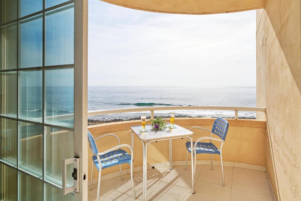 een balkon met een tafel en stoelen en de oceaan bij VENTANA AL ATLANTICO in El Médano