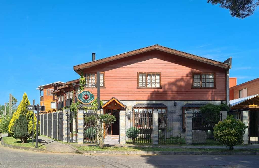 una casa roja con una valla delante en Hostal Collins House, en Temuco