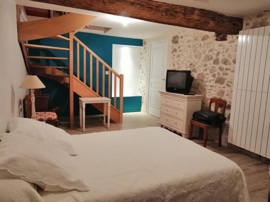 - une chambre avec un lit, un escalier et une télévision dans l'établissement Lavardac - Maison de Village Gascogne Landes, à Lavardac