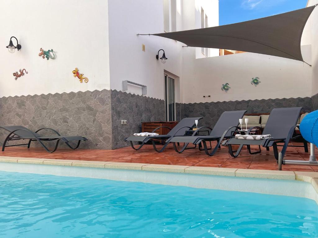 um pátio com cadeiras e uma piscina em Villa Pacifica em Corralejo