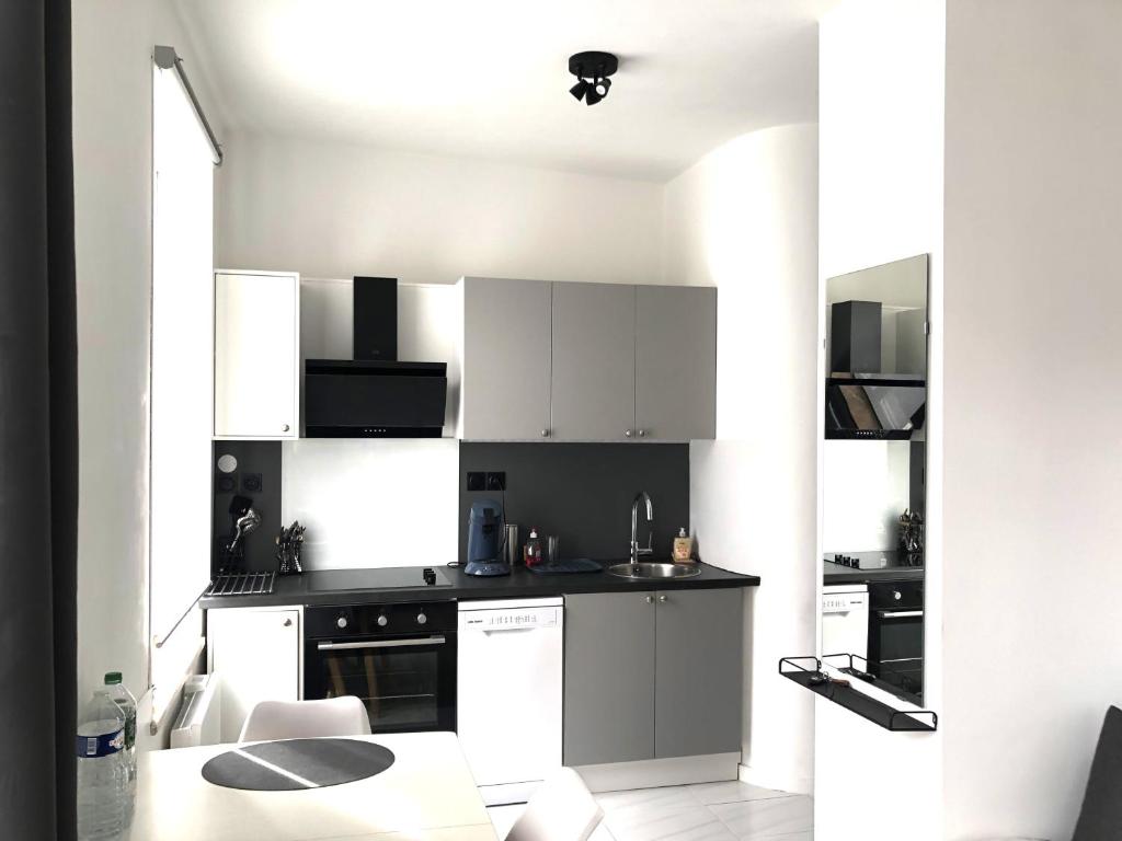 a small kitchen with white cabinets and a table at Charmant T2 centre ville in Givet